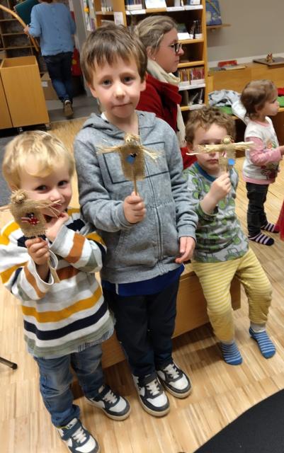 Kinder halten ihre selbstgebastelte Vogelscheuche in die Kamera