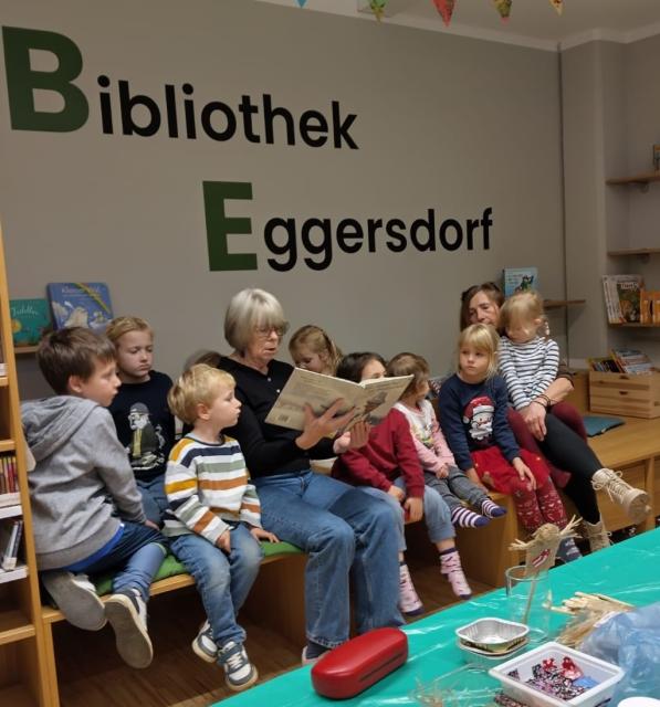 Kinder sitzen um Vorleserin